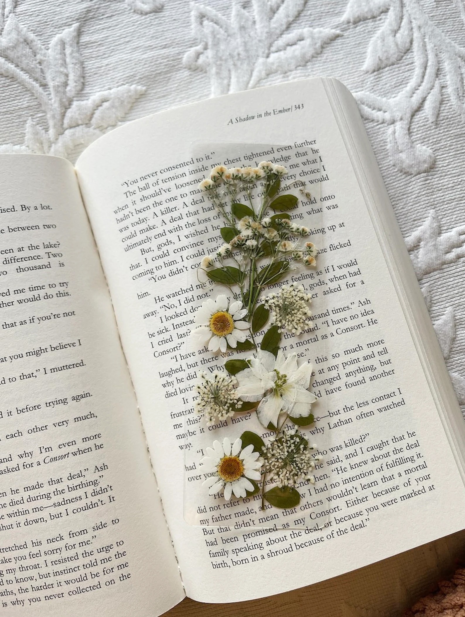 a photo of a resin bookmark that's filled with white wildflowers