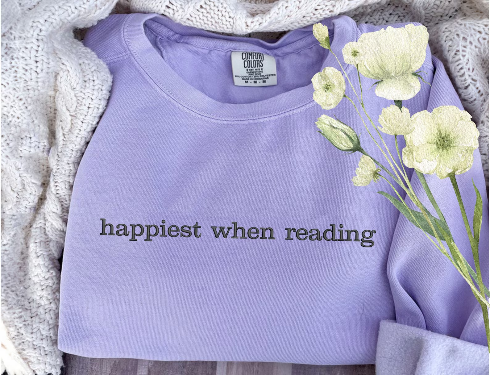 a photo of a purple sweatshirt embroidered with the words "happiest when reading"