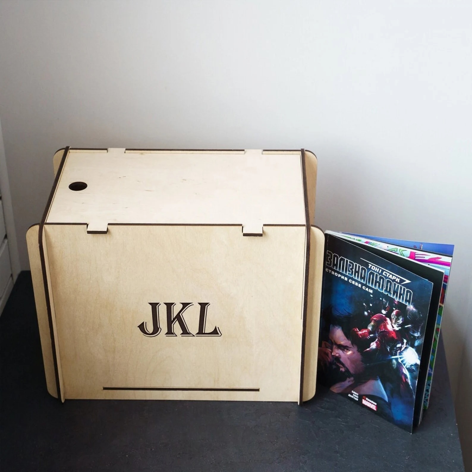 A pale box for holding comic books, with the initials JKL printed on the side