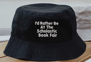 black bucket hat with sticking that says "I'd Rather Be At The Scholastic Book Fair"