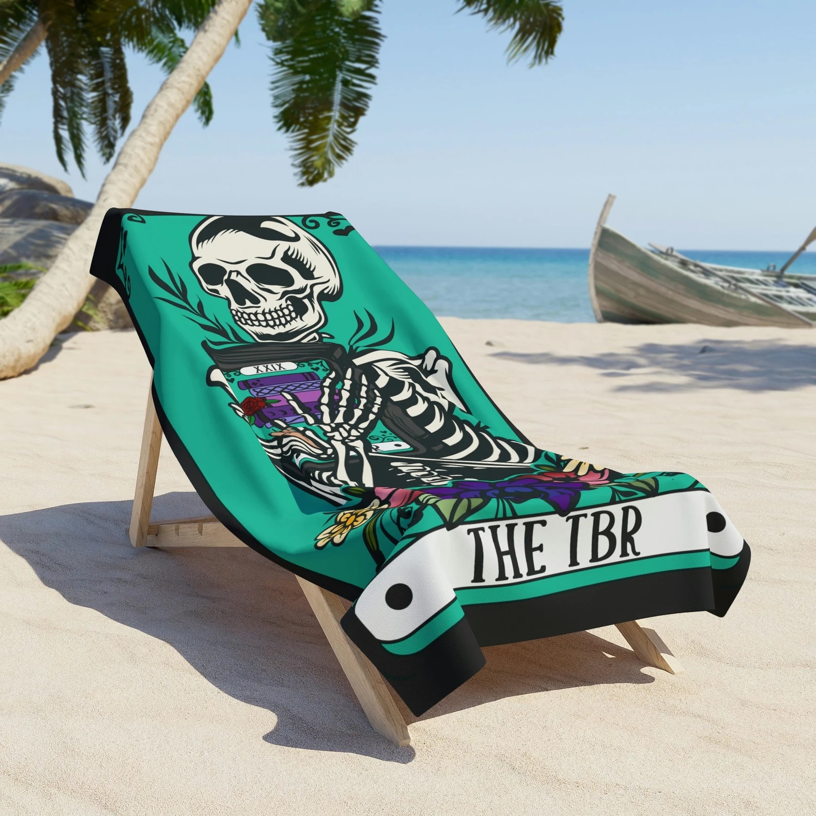 a photo a beach towel featuring a design of a tarot card. On the tarot is an illustration of a skeleton holding a stack of books.