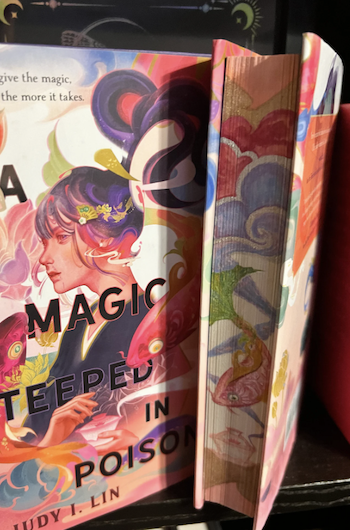 A hardcover edition of A Magic Steeped in Poison with its edge beautifully painted