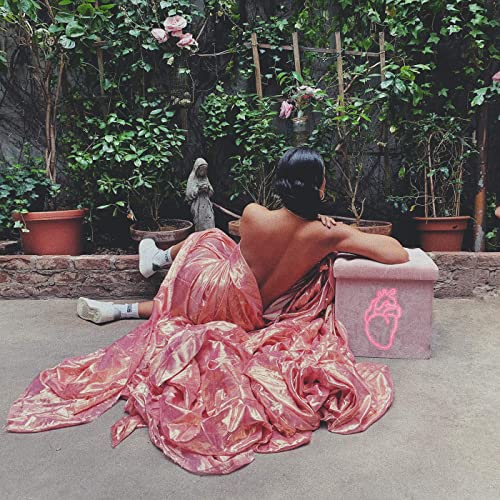 image of singer Amber Mark sitting with her back to the camera in a fluorescent pink and orange dress