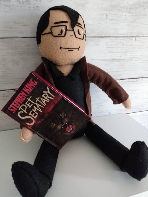 Felt doll of Stephen King holding a copy of Pet Semetary made by DeepCutCreations on Etsy