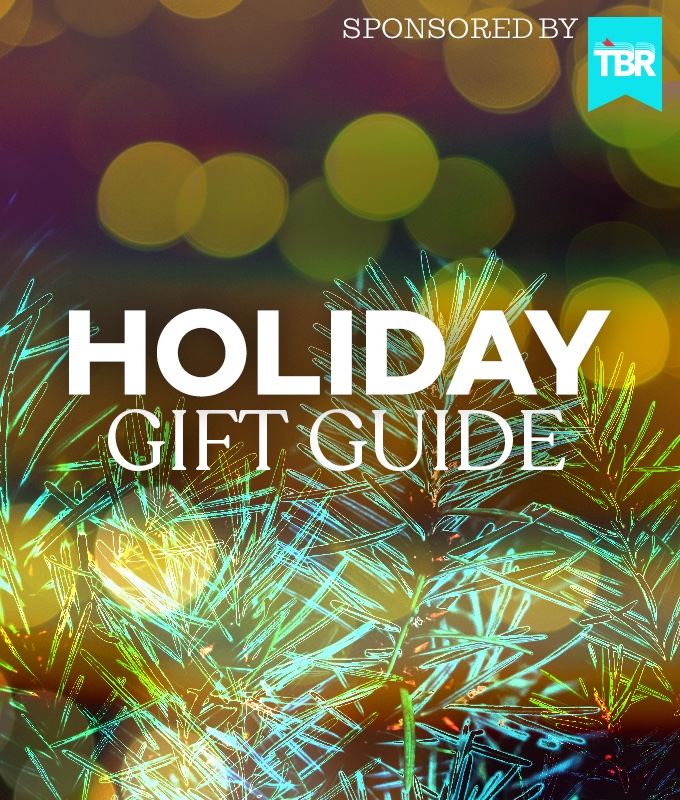a soft-focus photo of pine needles with golden glowing lights behind them, and the words HOLIDAY GIFT GUIDE sponsored by TBR
