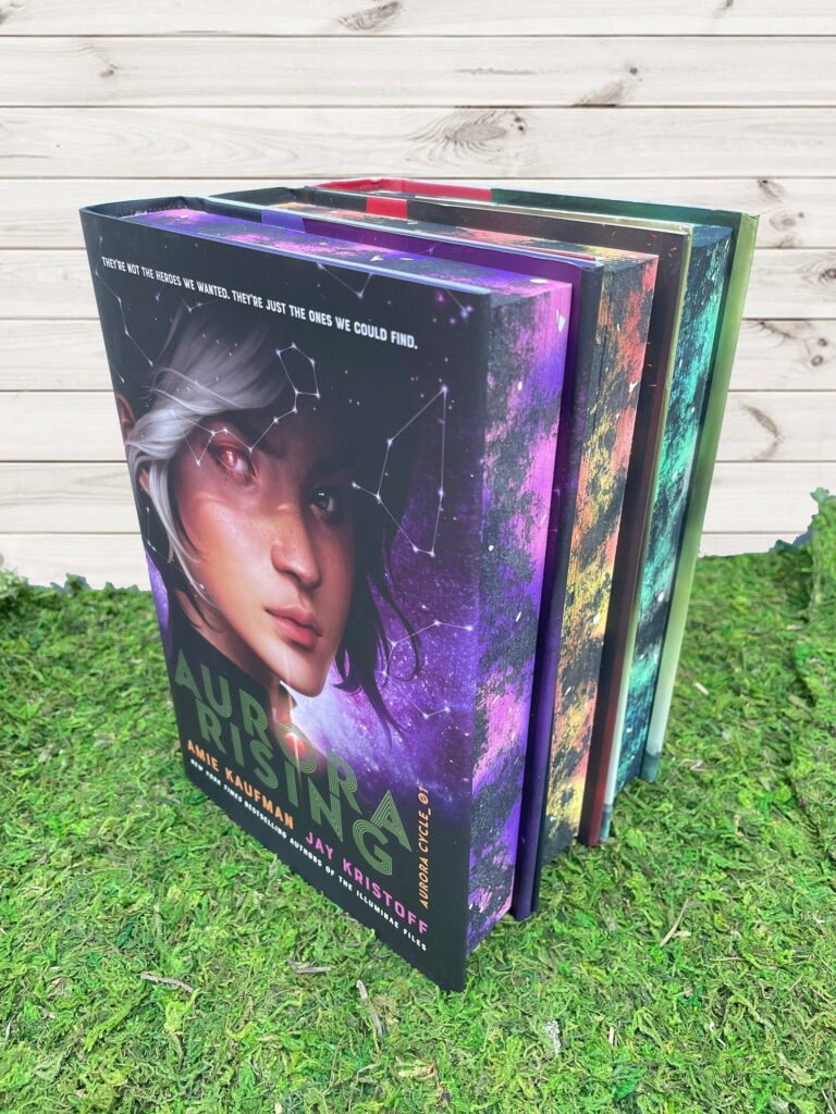 Image of the three books from the Aurora Rising series, each with a colorful galactic edge painting. 