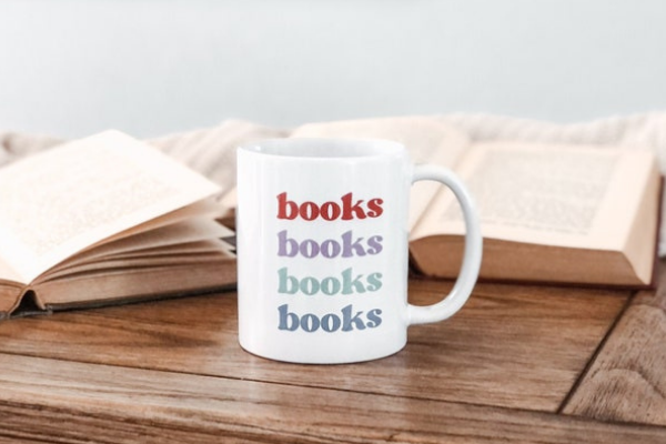 White mug with vintage, colorful font with the word "books" four times.