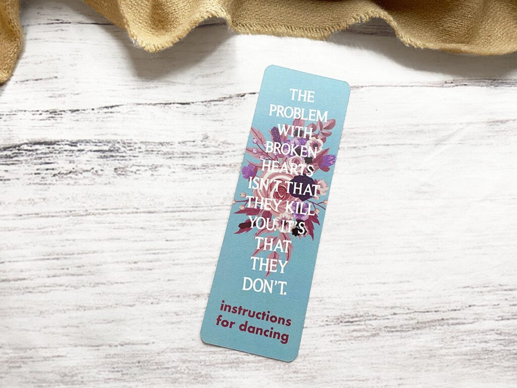 Image of a light blue bookmark with the quote "the problem with broken hearts isn't that they can kill you. it's that they don'." The quote is from Instructions for Dancing by Nicola Yoon.