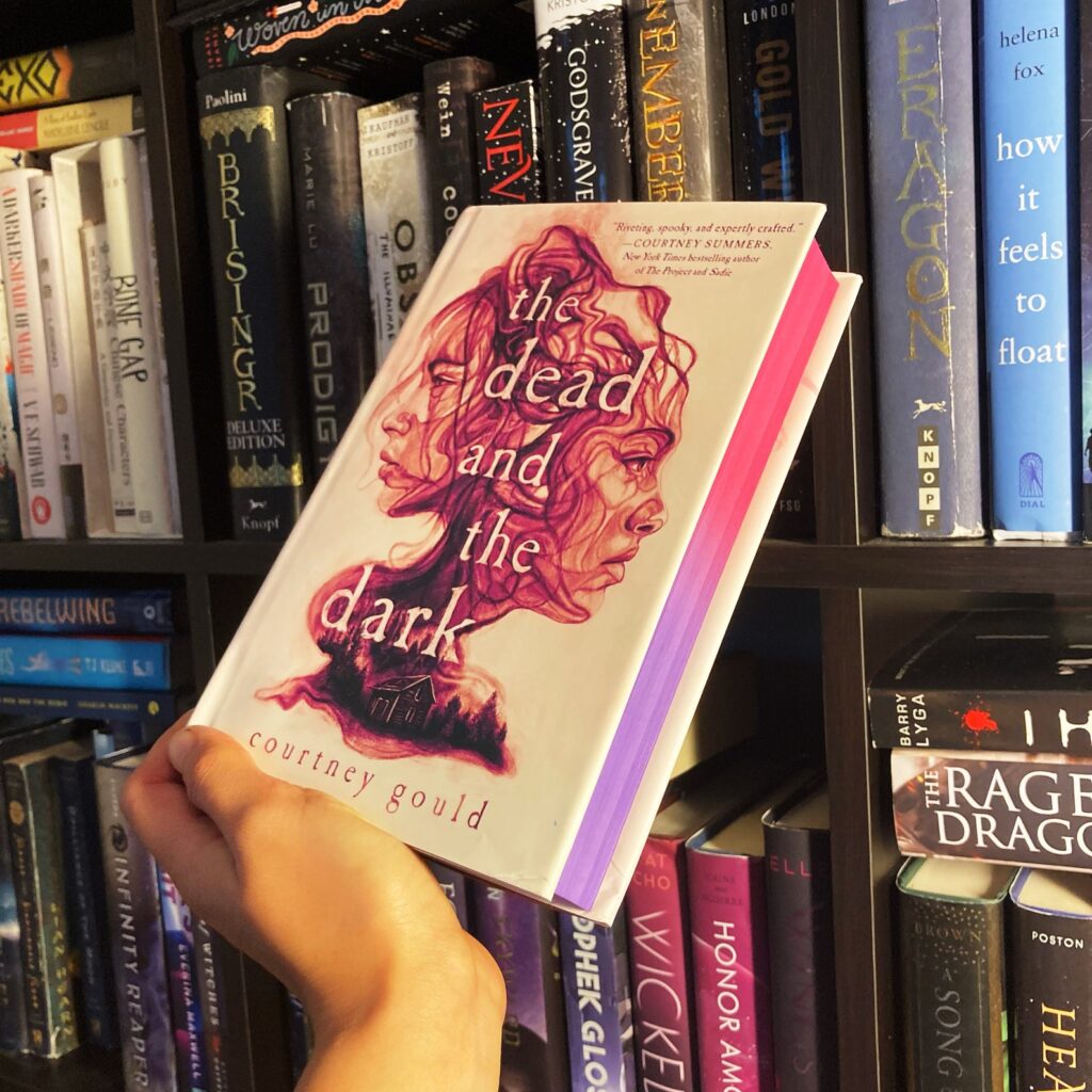 Image of the book The Dead and The Dark. The edges are sprayed pink and purple. 