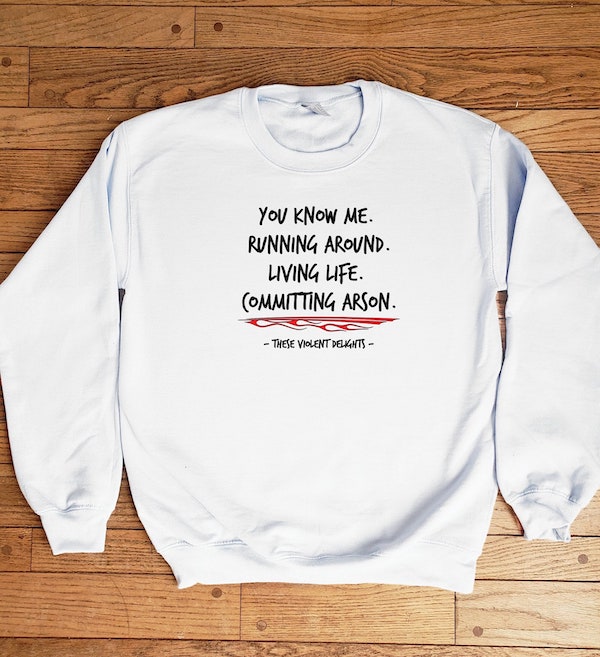 White sweatshirt with a quote from "These Violent Delights" on it: "You know me. Running around. Living life. Committing arson."