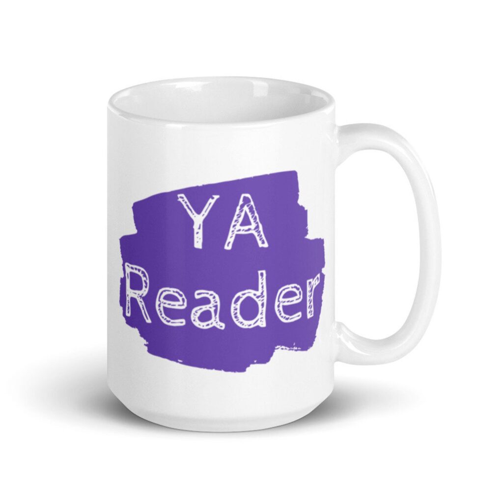 Image of a white mug with a splash or purple. The white text inside the purple reads "YA reader." 