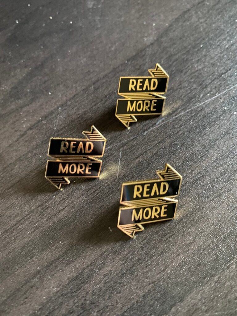 image of three pins. both are black and gold in the shape of a banner. the banners say "read more."