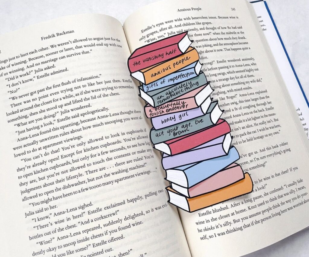 Image of a colorful stack of books bookmark. It is inside an open book. 