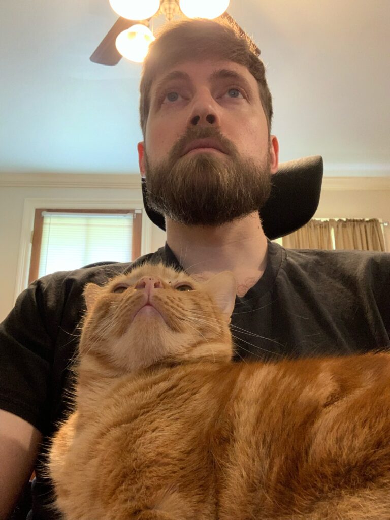 a photo of a man sitting in a computer chair with a cat