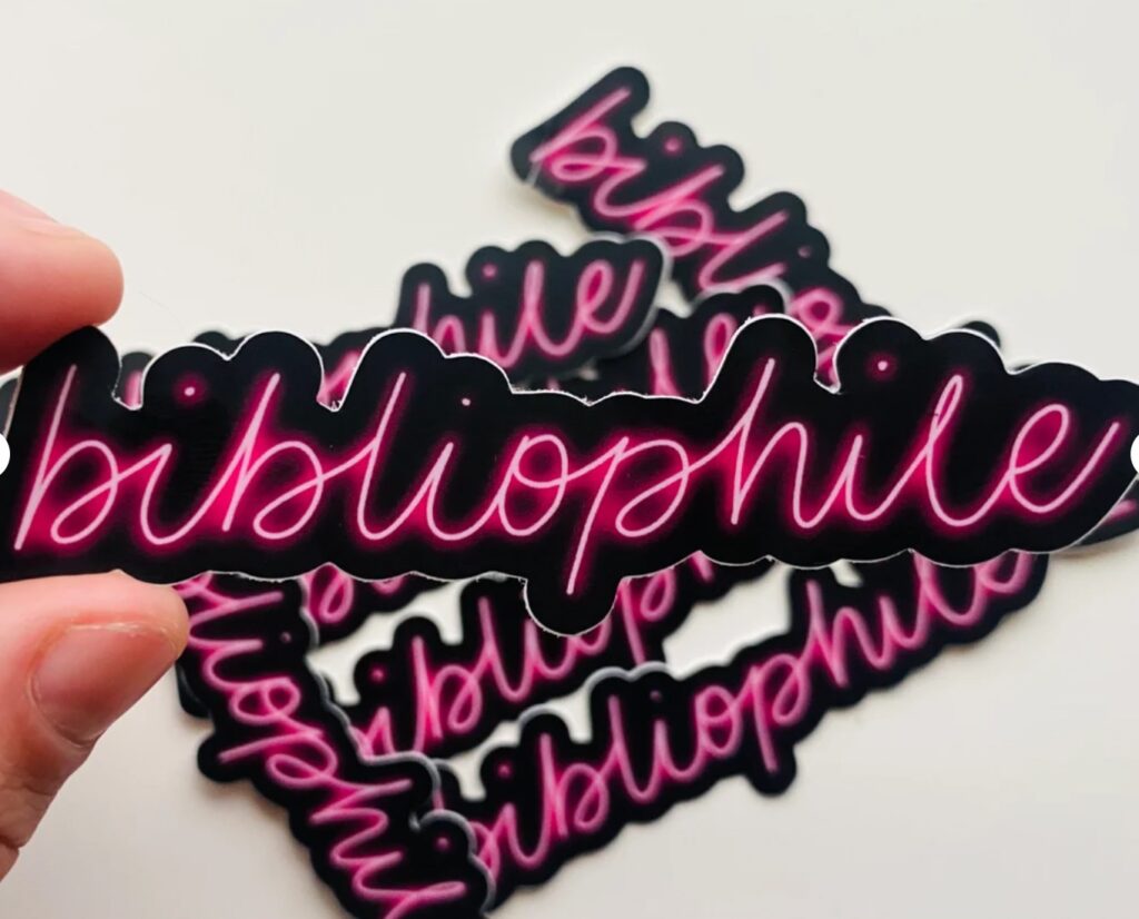 Black sticker with neon pink writing that reads "bibliophile."