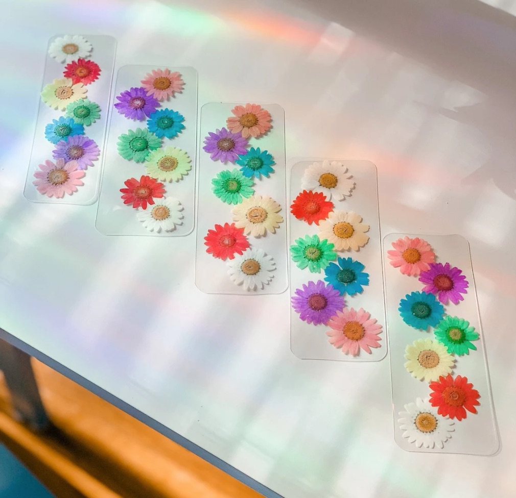 Image of 5 bookmarks. Each has a rainbow of pressed flowers. 