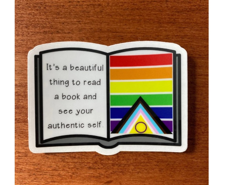 Image of a sticker in the shape of an open book. On one page is a Pride flag. On the other page are the words "it's a beautiful thing to read a book and see your authentic self."