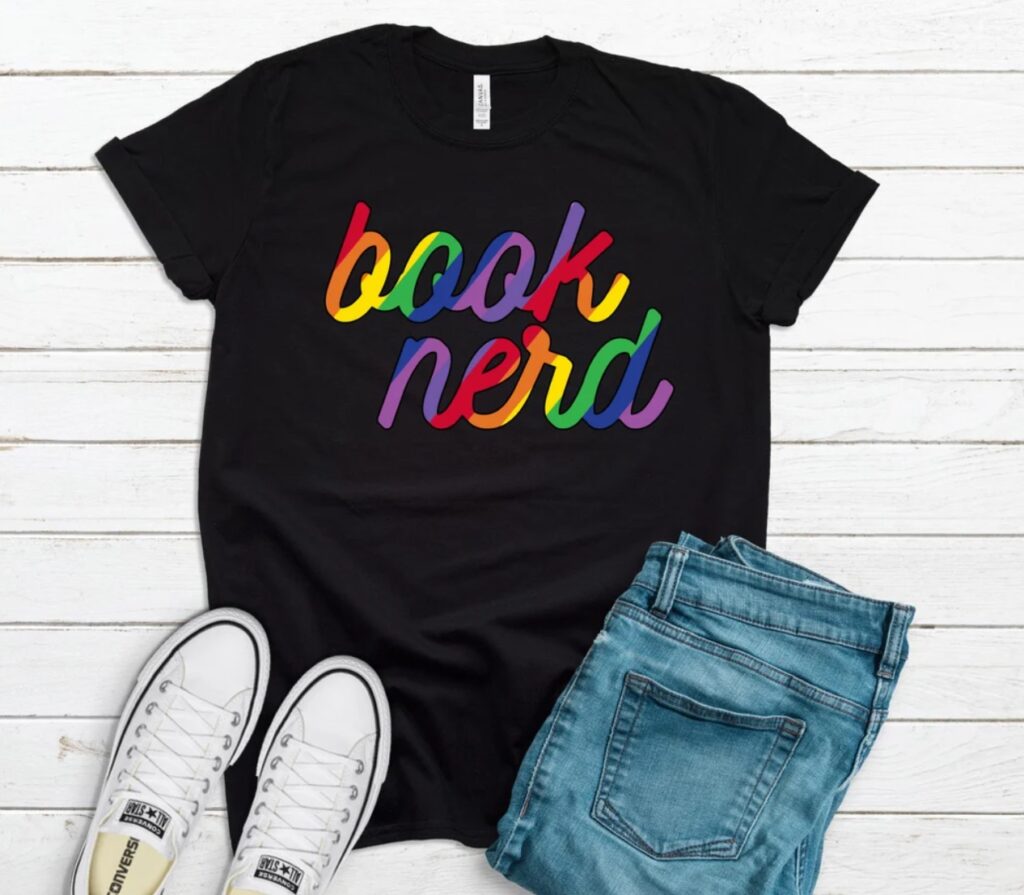 Black t-shirt on white background. The shirt says "book nerd" in rainbow colors. 