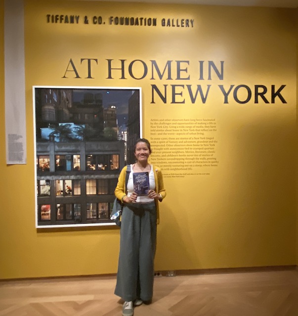 Karina Yan Glaser standing by the At Home in New York exhibit