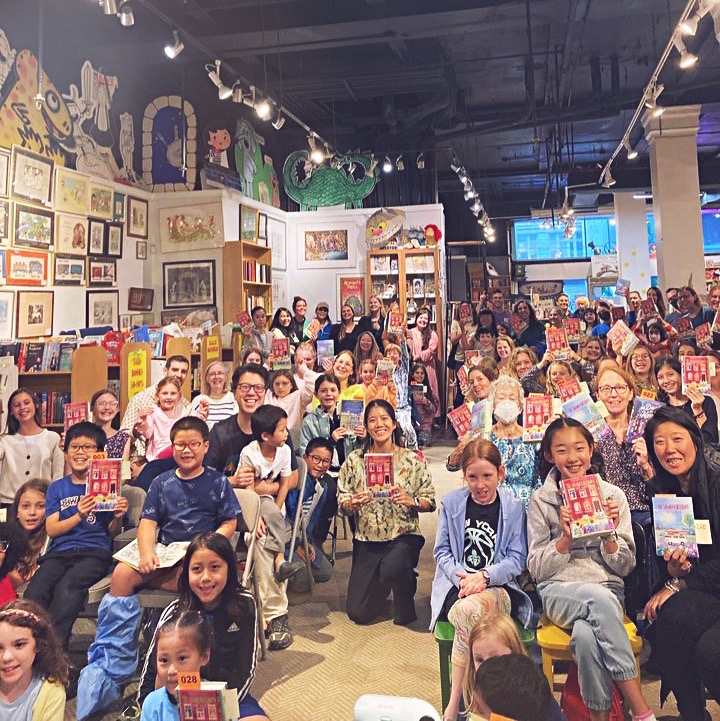 Many people in a bookstore holding up Vanderbeeker books